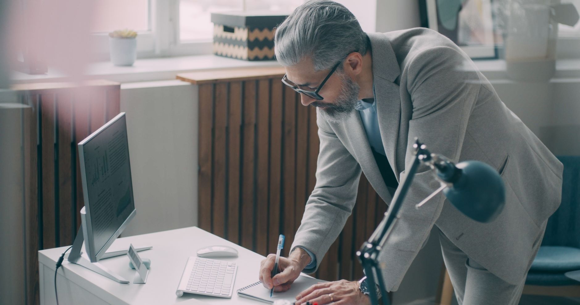 Älterer Mann mit Brille arbeitet an einem Schreibtisch im Büro