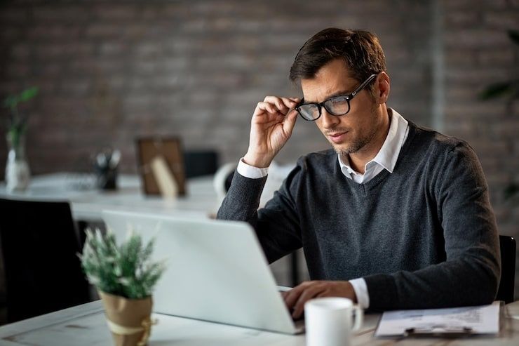 Mann mit Brille arbeitet konzentriert an einem Laptop am Schreibtisch